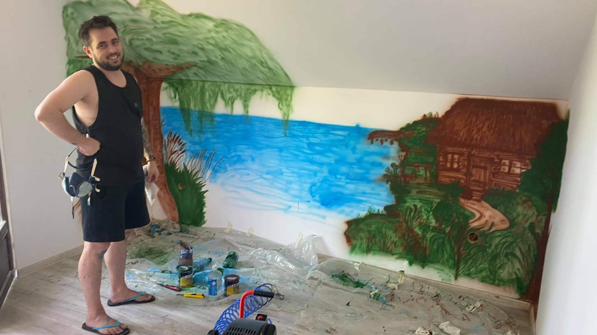 AndryArt beside a hand-painted mural